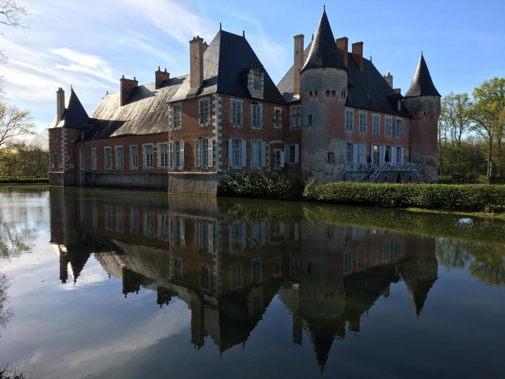 an old castle with its reflection in the water at Château de Souesmes in Souesmes