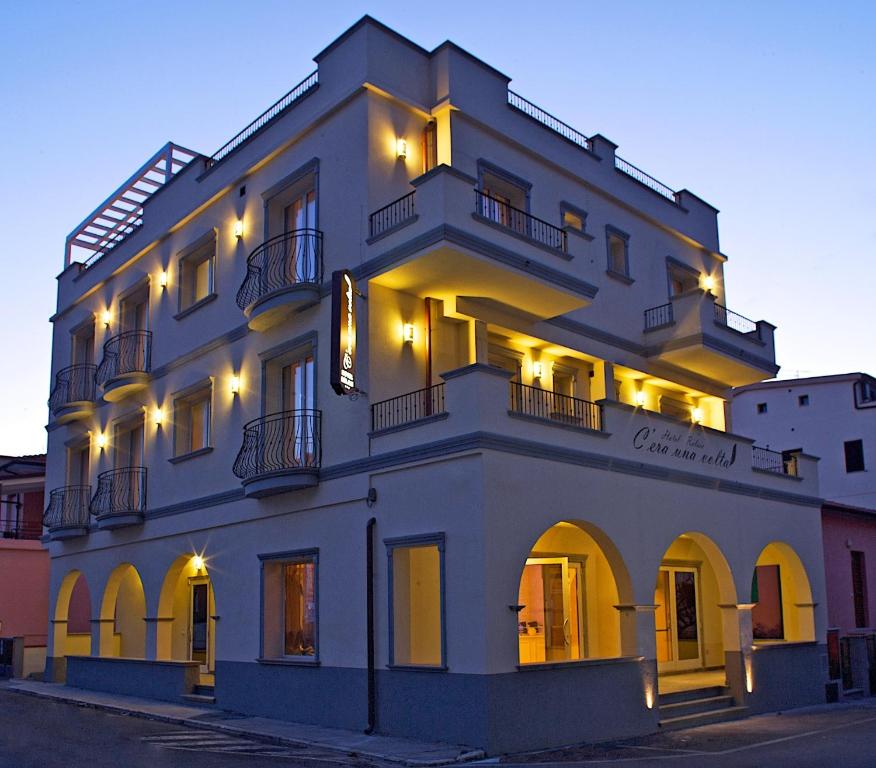 a large white building with lights on it at Hotel C'era Una Volta in Castiglione della Pescaia
