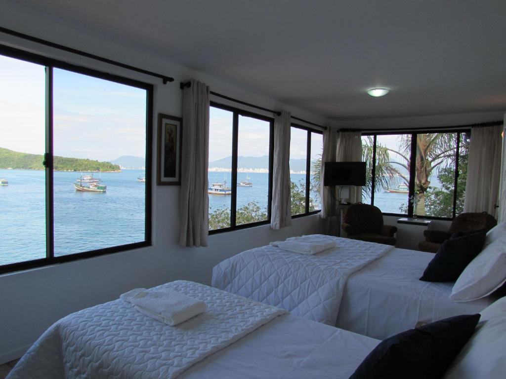 2 camas en una habitación con vistas al agua en Caixa D'aço Residence, en Porto Belo