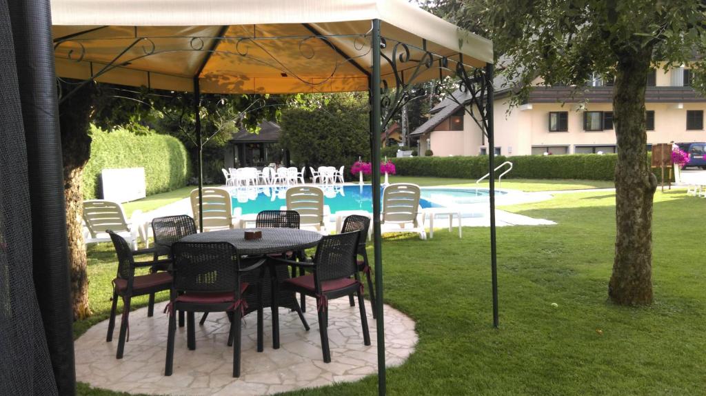 une table et des chaises sous une tente avec piscine dans l'établissement Sport Manca Garni Hotel, à Radovljica