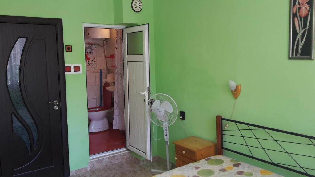 a bedroom with green walls and a bathroom with a fan at Dom Lidiya in Pomorie