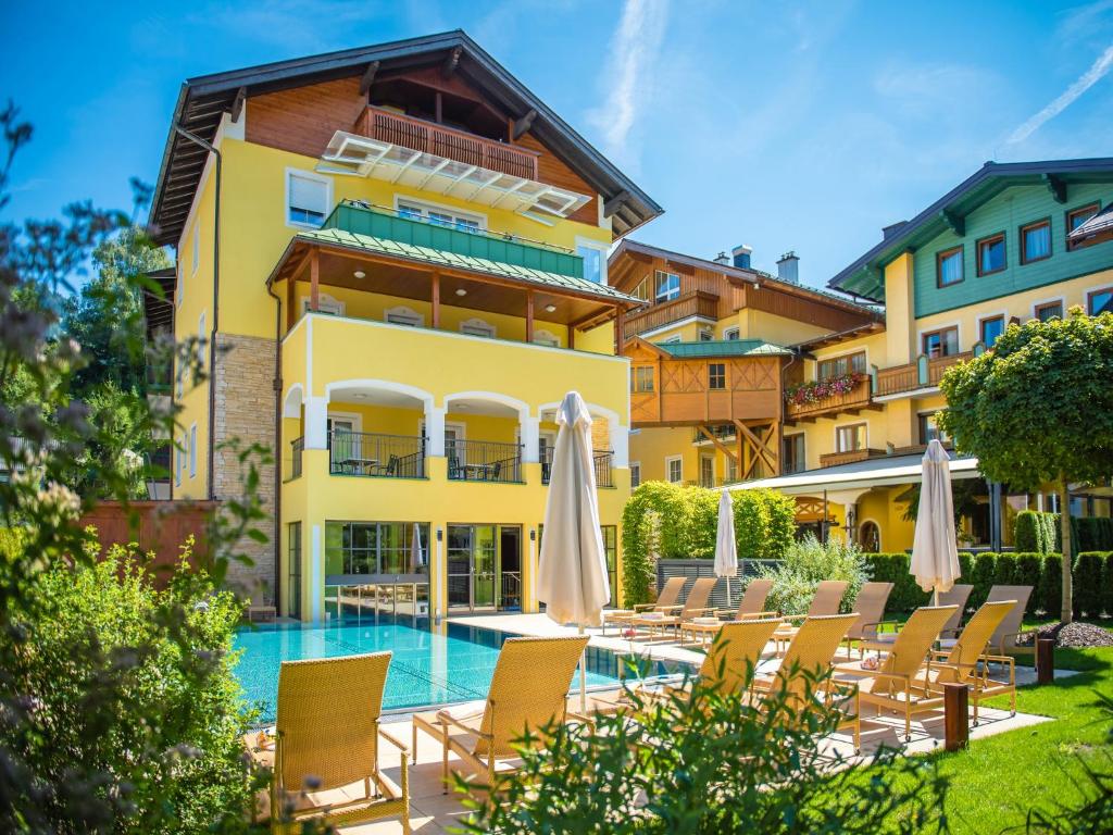 ein Hotel mit einem Pool, Stühlen und Sonnenschirmen in der Unterkunft Hotel Brückenwirt in St. Johann im Pongau
