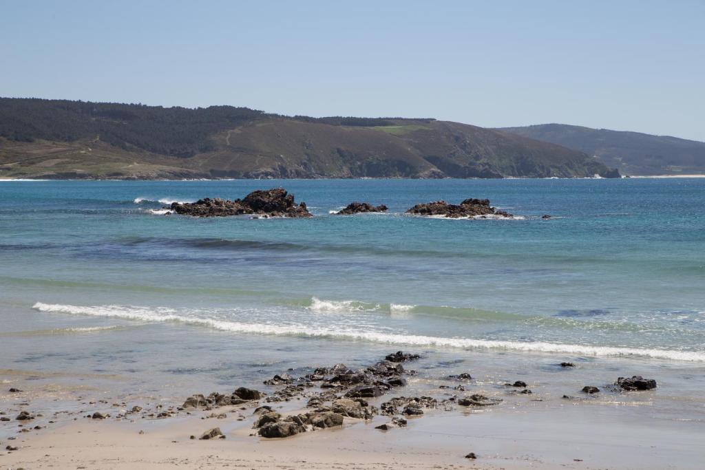 a beach with some rocks in the water at Casa das Fiadeiras de Nemiña in Nemiña