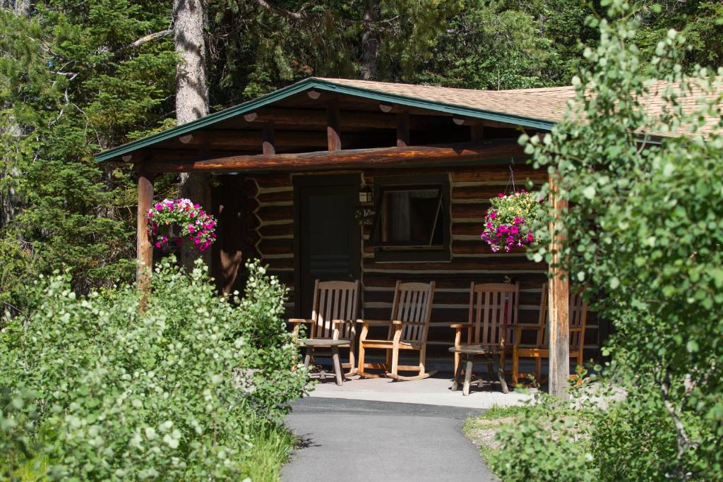 eine Hütte mit Stühlen und eine Veranda mit Blumen in der Unterkunft Jenny Lake Lodge in Beaver Creek
