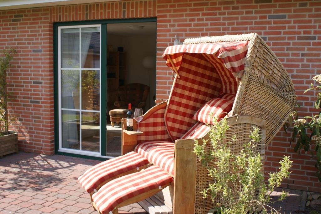 einen Korbstuhl mit roten und weißen Kissen auf einer Terrasse in der Unterkunft Beim Landarzt in Rabenholz