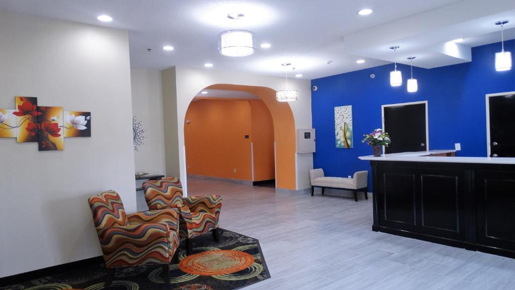 - un salon avec des murs et des chaises bleus et oranges dans l'établissement Oak Tree Inn & Suites, à Claxton