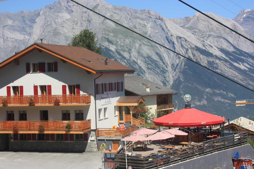 a building with a restaurant with mountains in the background at Hotel Les Etagnes in Nendaz