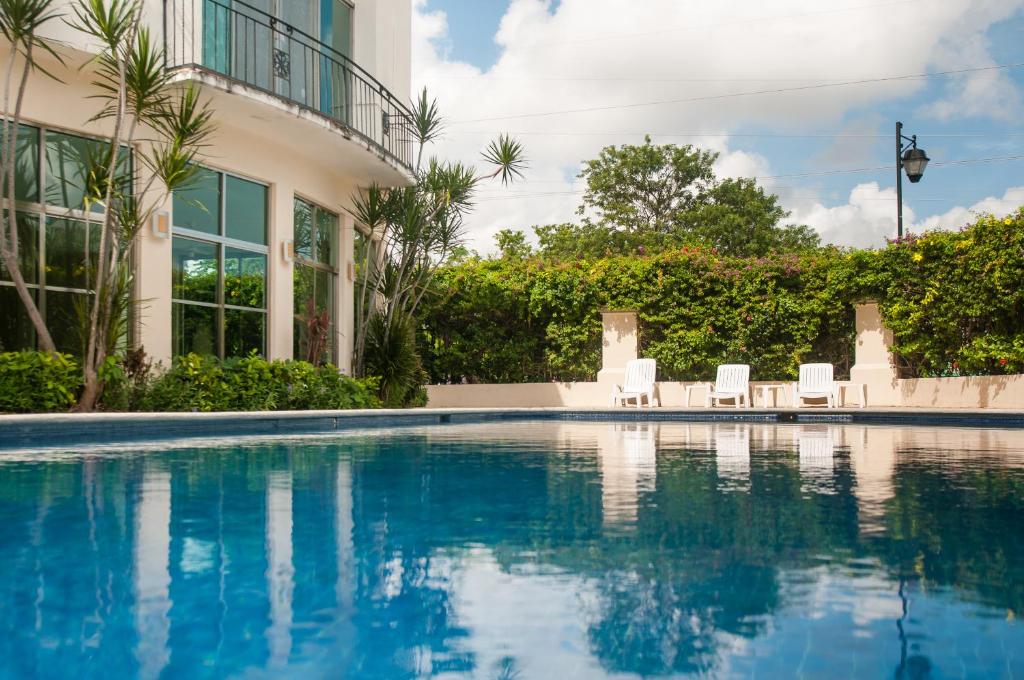 een zwembad met stoelen en een gebouw bij Boutique House Cancun by Elevate Rooms in Cancun