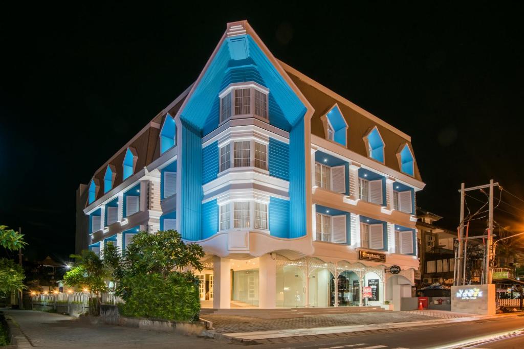 a blue and white building on a street at night at Yan's House Hotel in Kuta