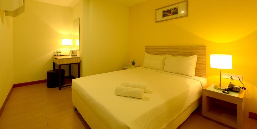 a bedroom with a large white bed and a desk at Hotel Sentral Kuala Terengganu in Kuala Terengganu