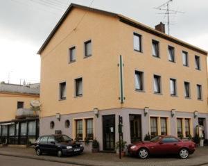 un grand bâtiment avec deux voitures garées devant lui dans l'établissement Hotel-Restaurant Bürgerstuben, à Lebach