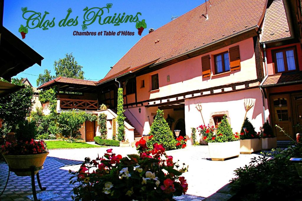 une maison avec des arbres de Noël et des fleurs dans une cour dans l'établissement B&B Le Clos des Raisins, à Beblenheim