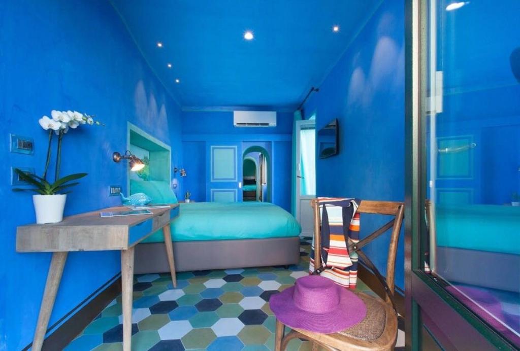 Dormitorio azul con cama, mesa y silla en Estate4home - La Grotta Azzurra, en Sorrento