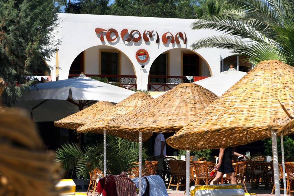 a group of straw umbrellas in front of a restaurant at Toloman Hotel Bitez Beach in Bitez