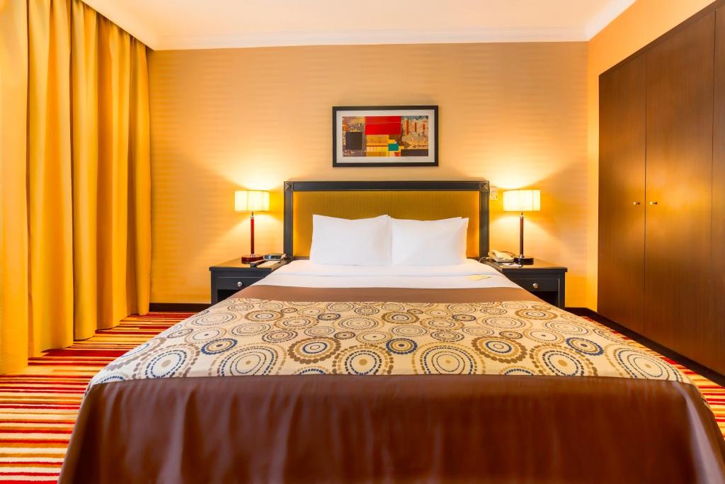 a hotel room with a bed and two lamps at Executive Suites Abu Dhabi in Abu Dhabi