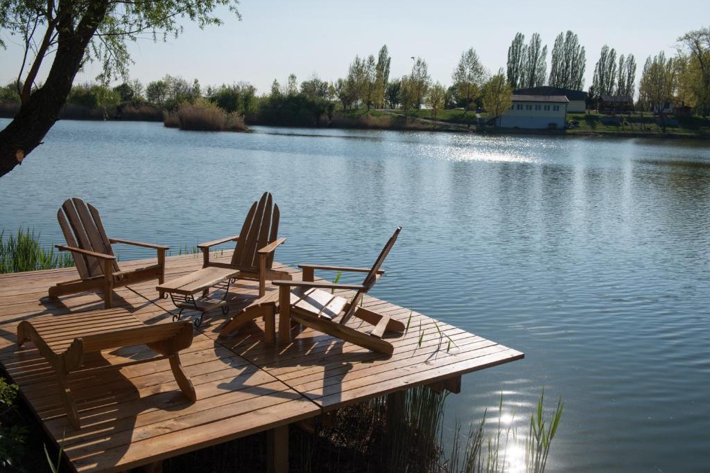 2 Stühle und ein Tisch auf einem Steg auf einem See in der Unterkunft Apartman Tímea in Dunajská Streda