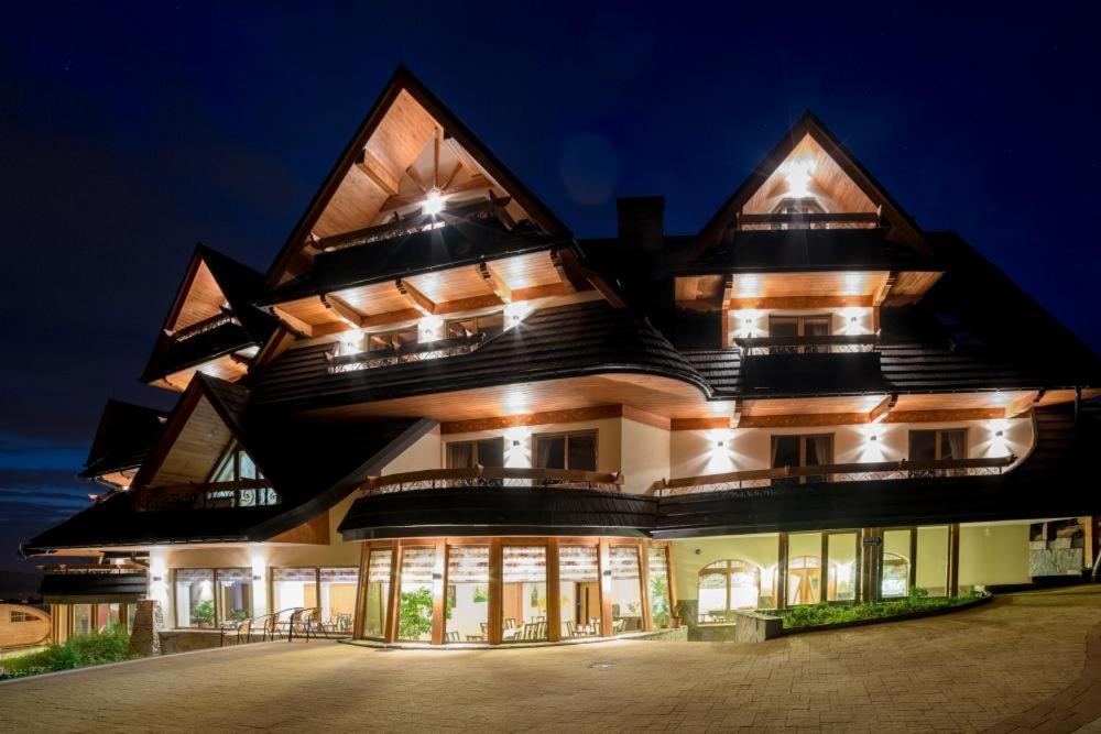 un gran edificio con un techo puntiagudo por la noche en Montenero Resort&Spa en Czarna Góra