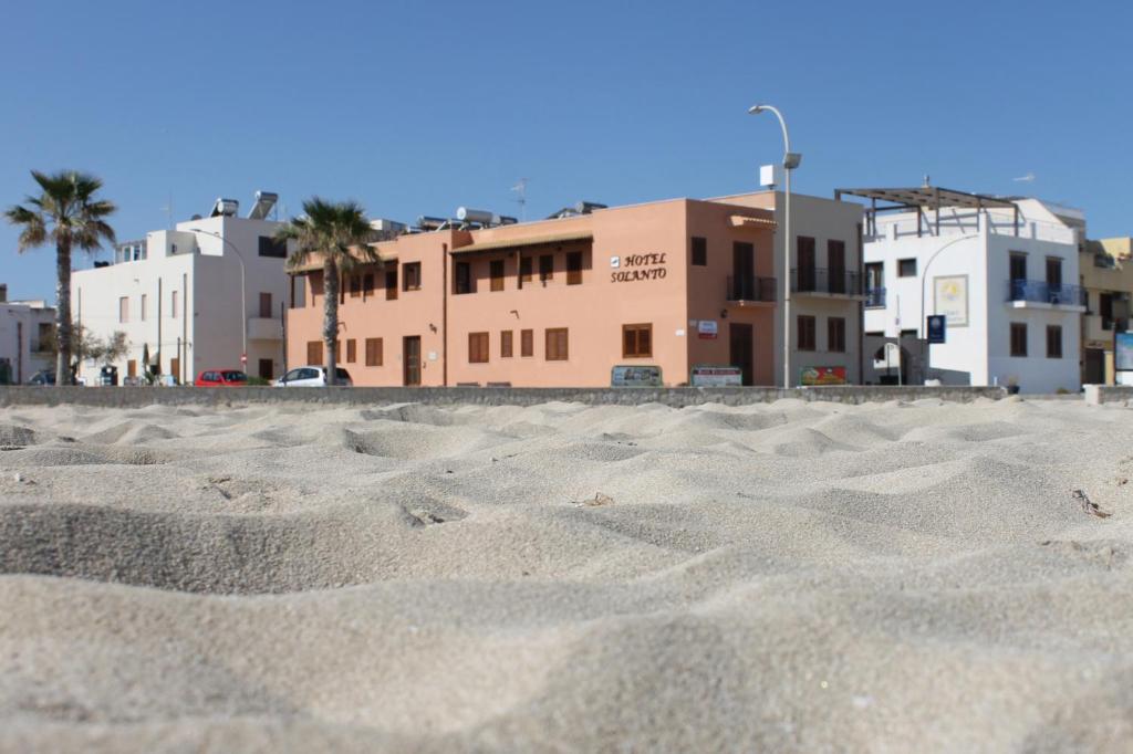 a view of a sandy beach with buildings in the background at Hotel Sòlanto in San Vito lo Capo