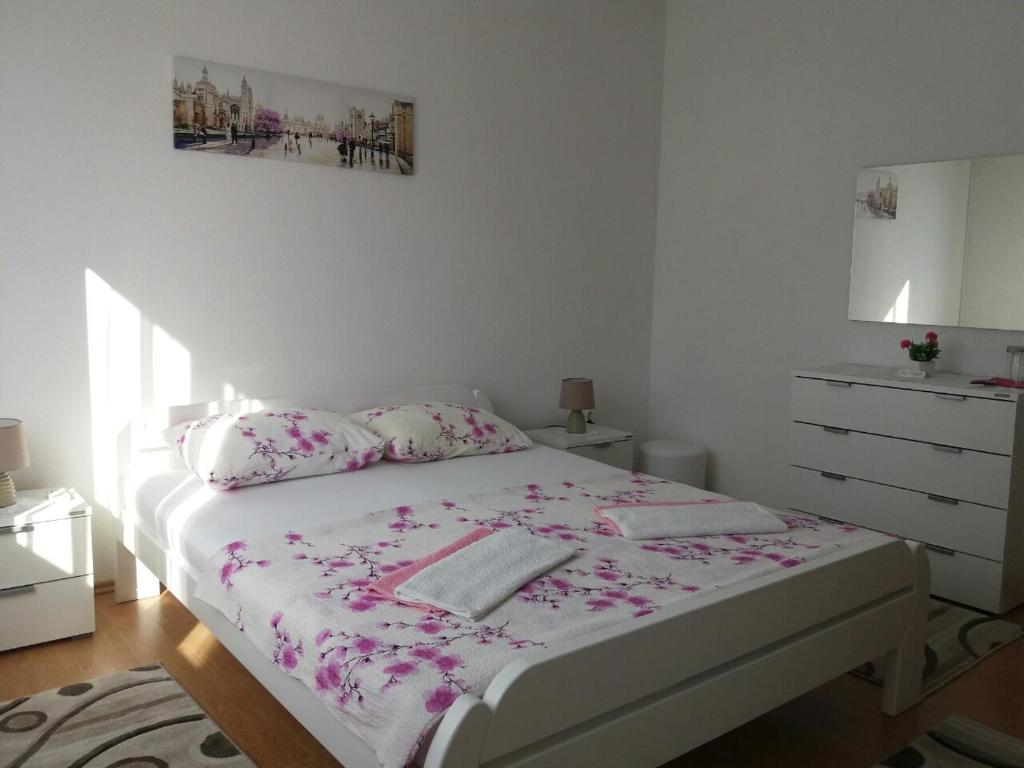 特雷比涅的住宿－康納克丹科旅館，白色卧室,配有带粉红色鲜花的床