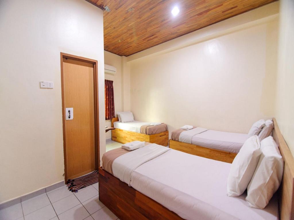een slaapkamer met 2 bedden en een deur naar een kamer bij Y&Z Hotel in Melaka