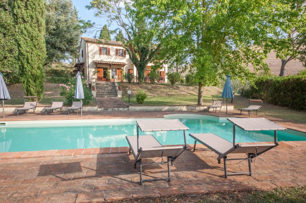 una piscina con sillas y sombrillas junto a una casa en Villa Gemelli, en Volterra