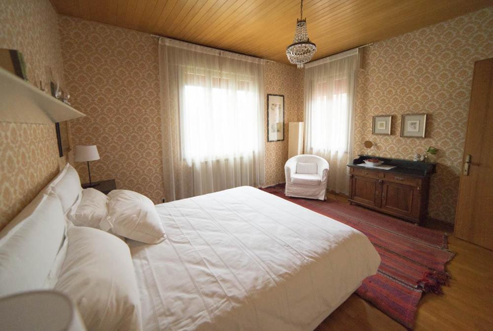 um quarto com uma grande cama branca e uma cadeira em dalla manu em Treviso