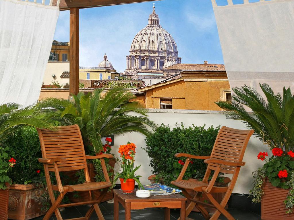 two chairs and a table on a balcony with a cathedral at Hotel Arcangelo in Rome