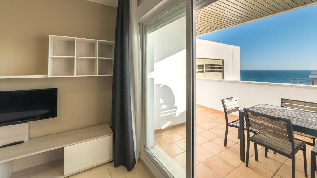 balcón con mesa de comedor y vistas al océano en Apartamentos Costa Luz Punta Umbría, en Punta Umbría