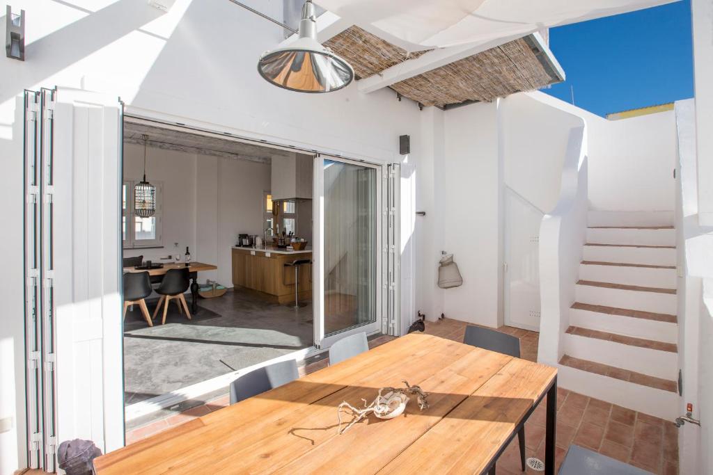a dining room with a wooden table and a staircase at Casa Opala Townhouse met Rooftop Pool in Olhão