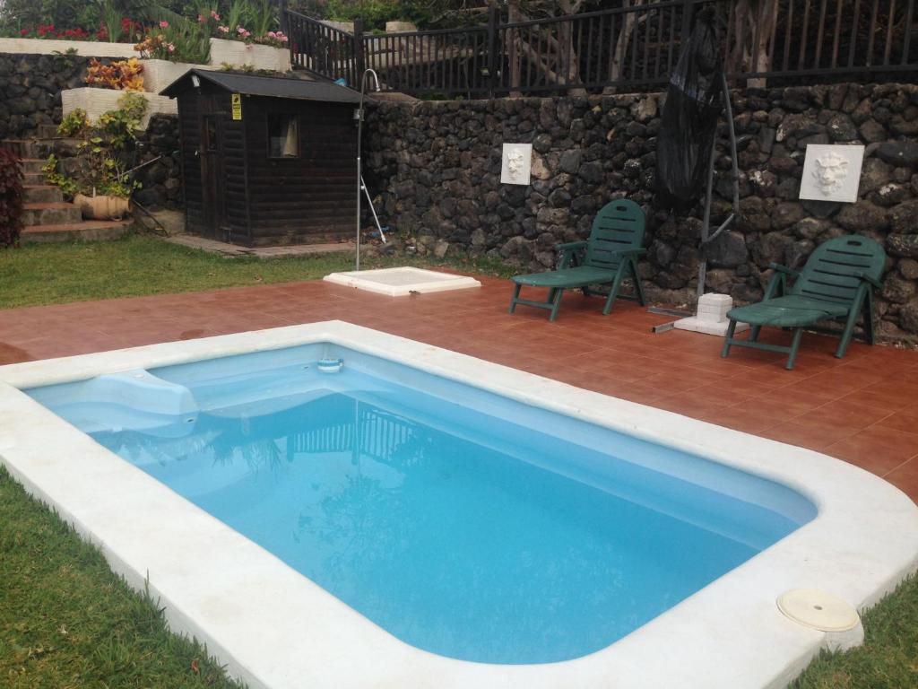 a swimming pool in a yard with two chairs at Finca El Cantero in Garachico