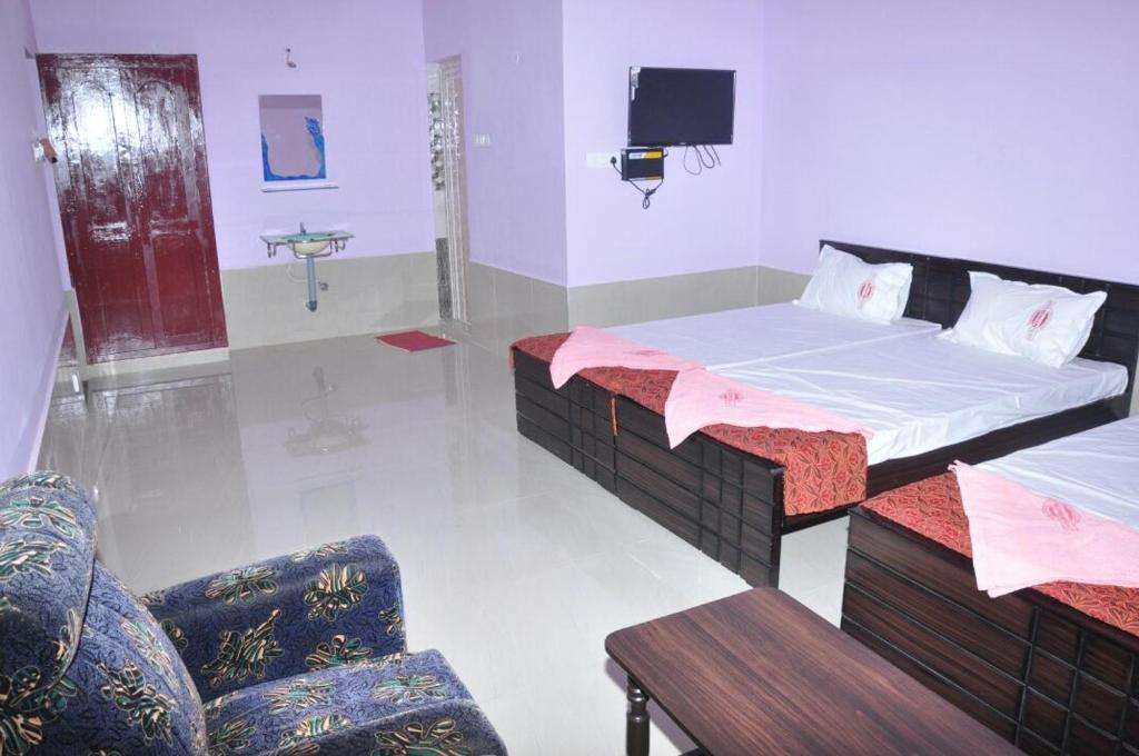 a room with two beds and a tv in it at Hotel Nippon Palace in Tarangambādi