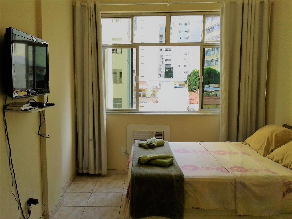 1 dormitorio con cama, ventana y TV en Copacabana POSTO 4 Temporada, en Río de Janeiro