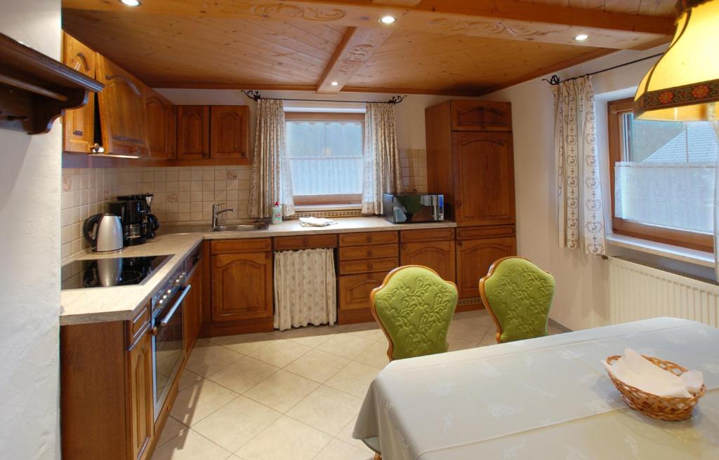 eine Küche mit Holzschränken sowie einem Tisch und Stühlen in der Unterkunft Ferienwohnung Gebirgshäusl in Bischofswiesen