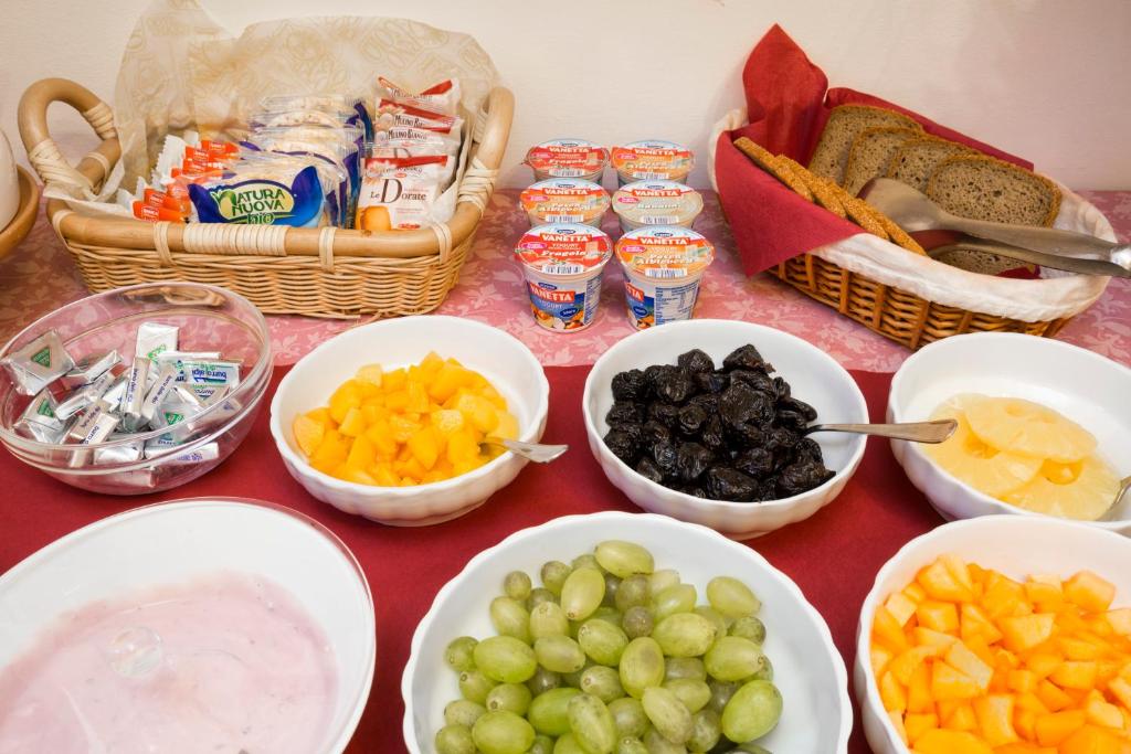 a table topped with bowls of fruit and baskets of bread at Villa Casanova in Venice-Lido