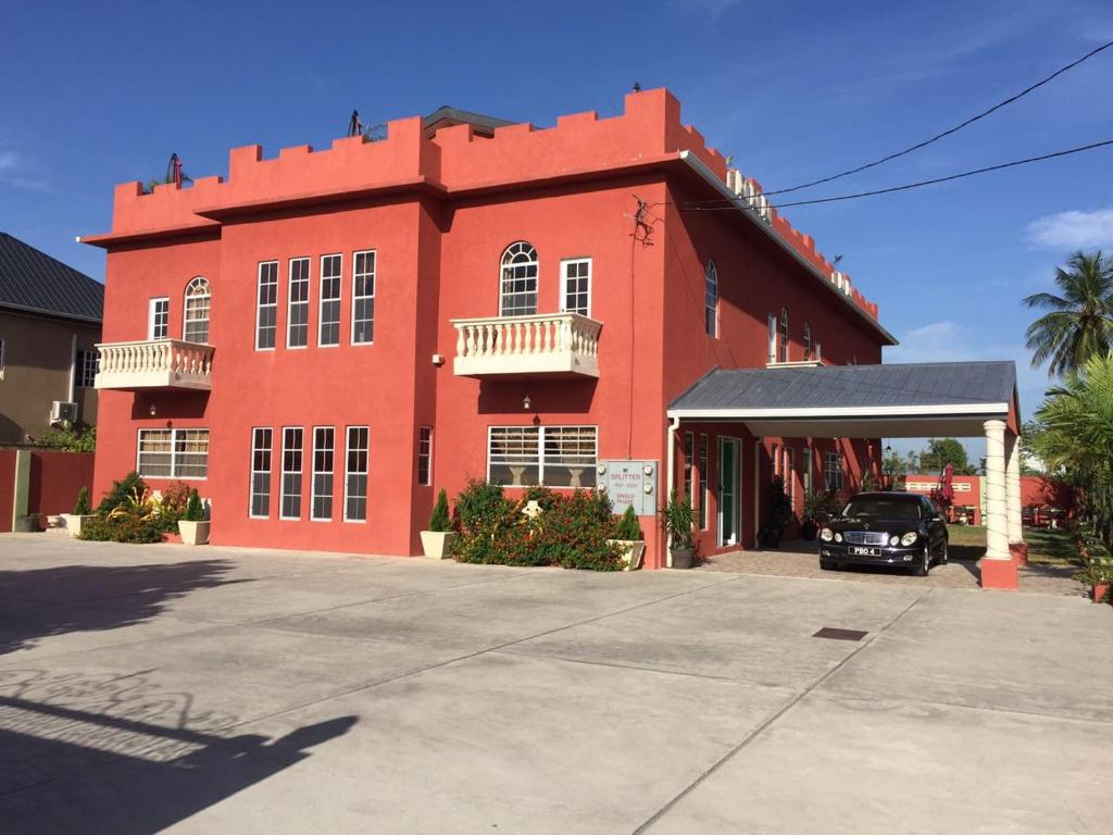 ein rotes Gebäude mit einem davor geparkt in der Unterkunft Montecristo Inn in Piarco