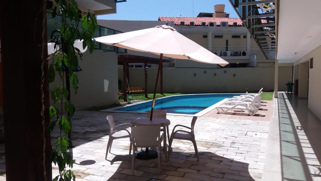 een tafel met een parasol naast een zwembad bij Manawa Beach Flats Prime in Porto De Galinhas