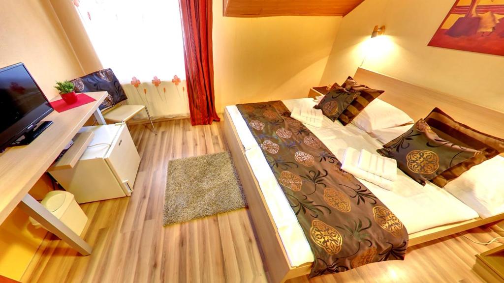 een slaapkamer met een bed en een bureau met een televisie bij Penzion Siesta in Vráble