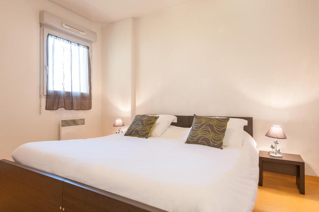a bedroom with a large white bed and a window at City Résidence Lyon Marcy in Marcy-lʼÉtoile