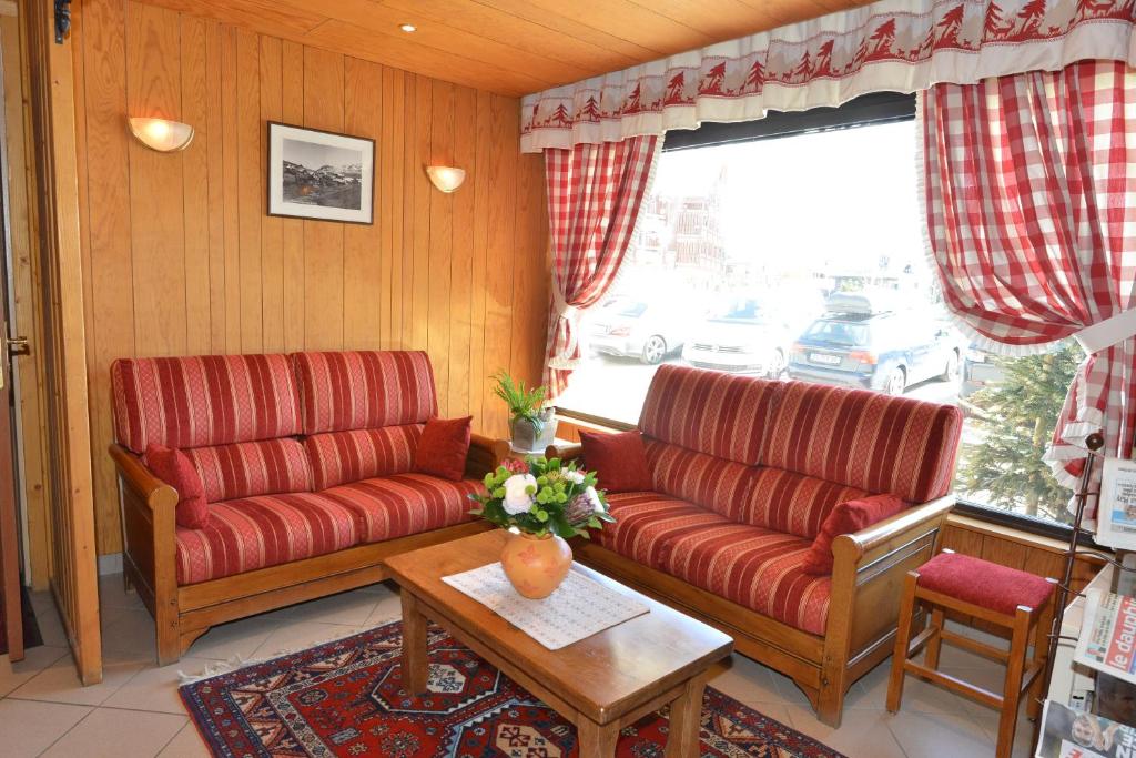 a living room with two red couches and a table at Hôtel Le Dôme in L&#39;Alpe-d&#39;Huez