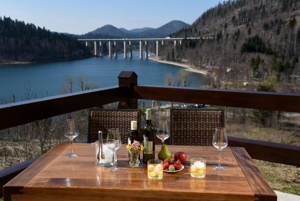 a wooden table with wine glasses and a view of a bridge at Villa MOYA in Fužine