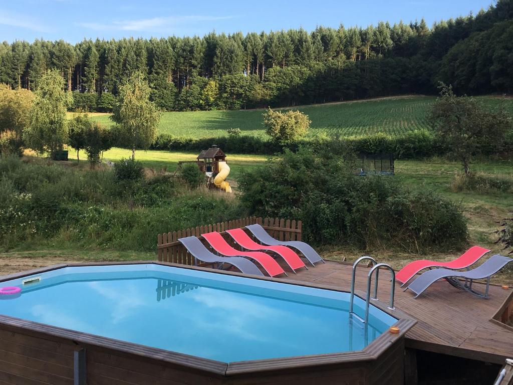 a pool on a deck with two chairs and a woman holding an umbrella at Forét Enchantée De Bourgogne in La Celle-En-Morvan