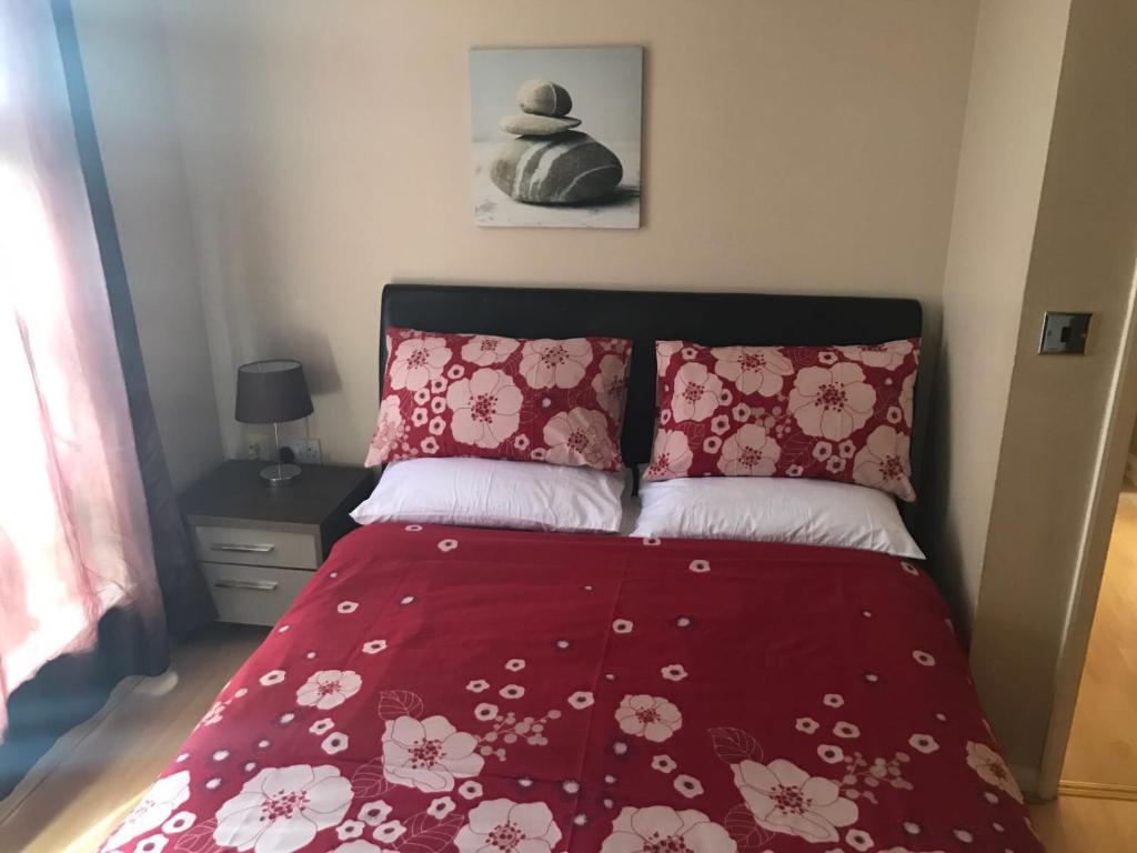 - un lit avec une couette rouge et 2 oreillers dans l'établissement Charlesmere gardems, à Londres