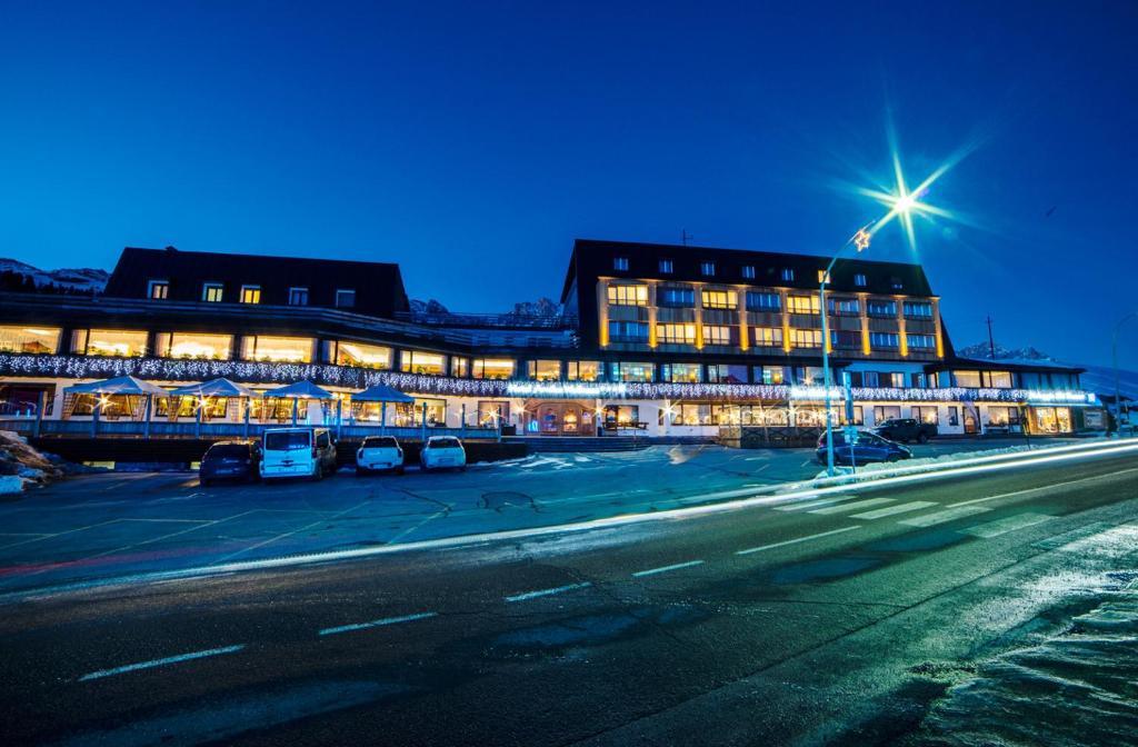 a building with cars parked in a parking lot at night at Hotel Arnika Wellness in Passo San Pellegrino