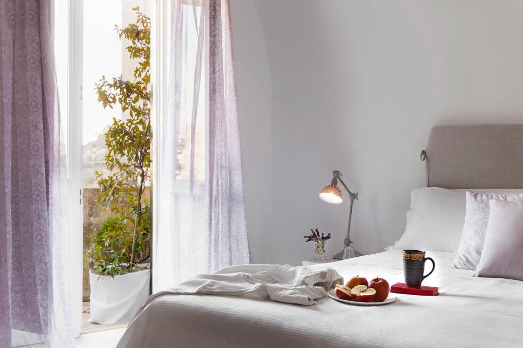 マテーラにあるAngolo del Poeta - Maison de Charmeのベッド(窓際にフルーツを入れたボウル付)