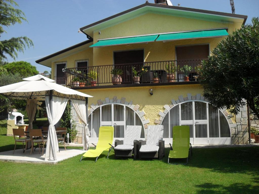 une maison avec des chaises, une table et un parasol dans l'établissement Casa Romantica, à Bardolino