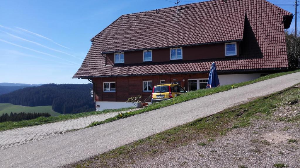 ein Haus an der Seite eines Hügels mit einem gelben Bus in der Unterkunft Pension Forsthaus Täle in Titisee-Neustadt