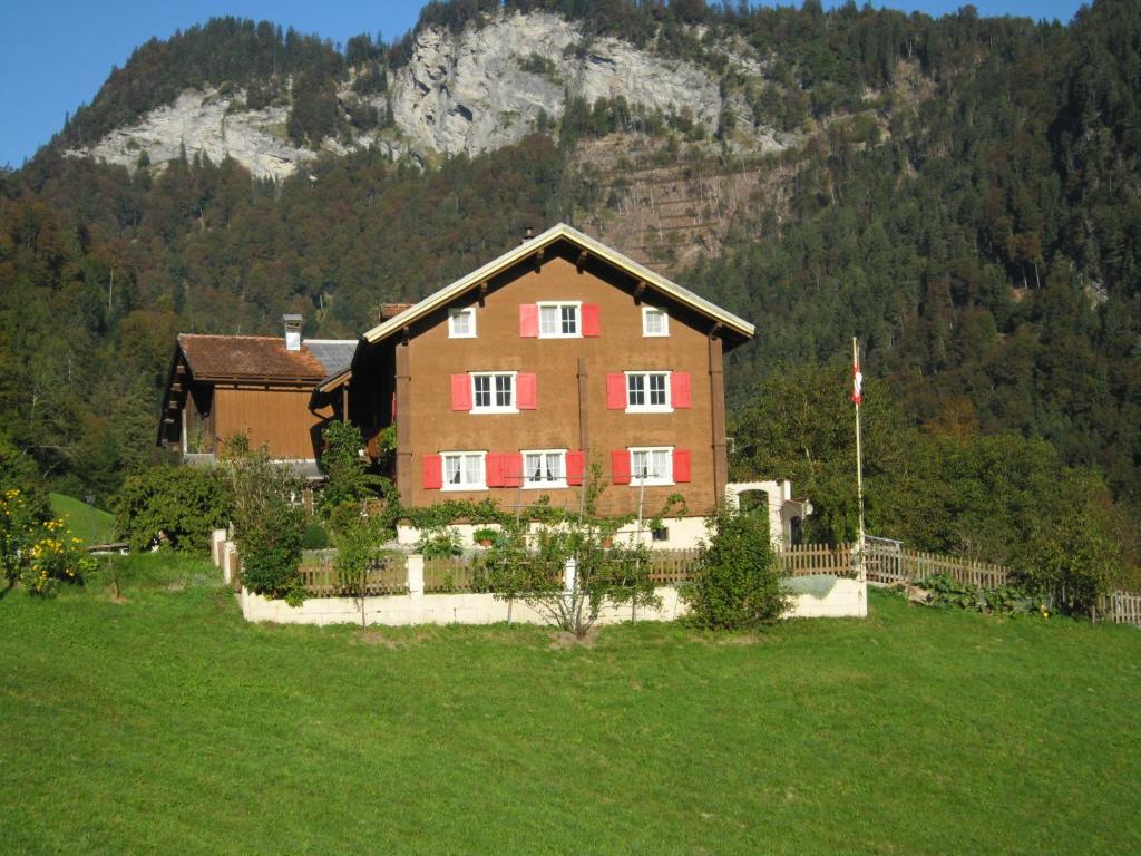 a large house in a field in front of a mountain at B&B Härihof in Grüsch