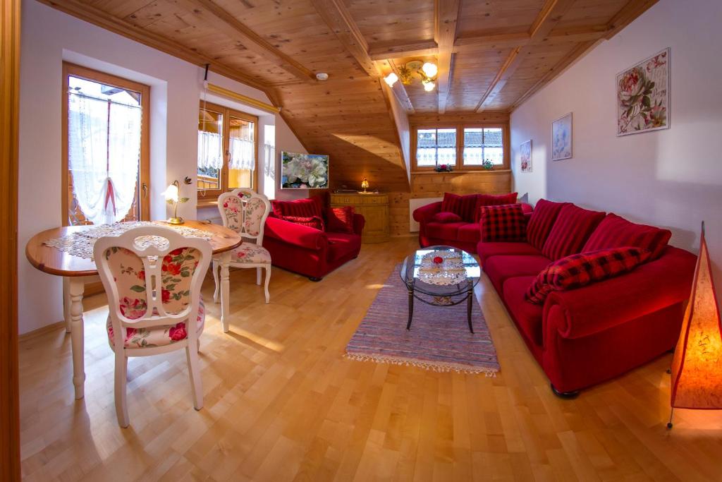 ヴェルタハにあるFerienwohnung mit eigener Saunaのリビングルーム(赤いソファ、テーブル付)