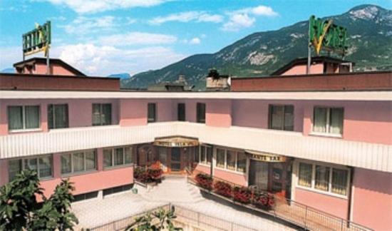 een roze en wit gebouw met bergen op de achtergrond bij Hotel Vela in Trento