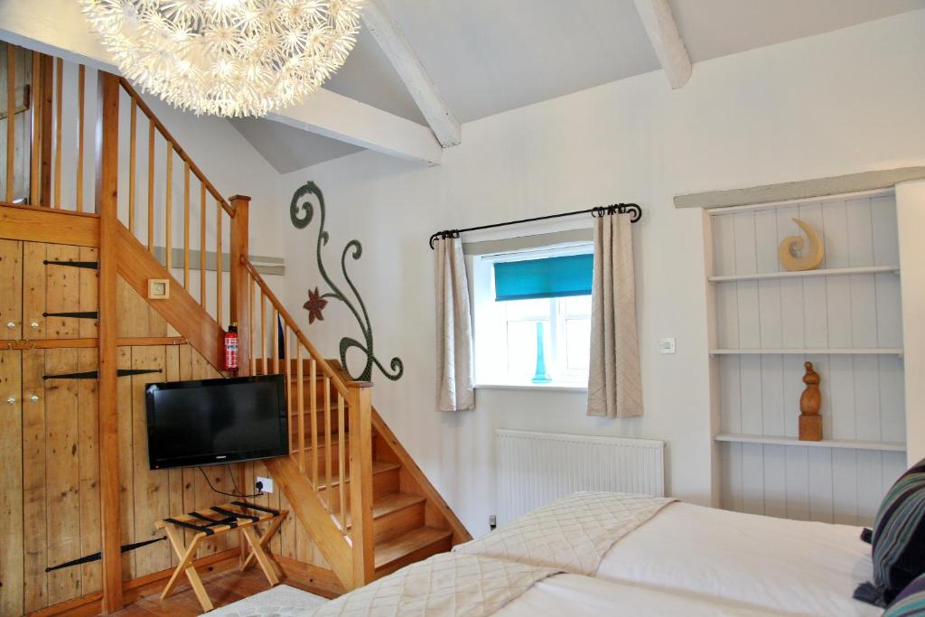 a bedroom with a bed and a staircase with a tv at Greenbanks Hotel Norfolk in Great Fransham